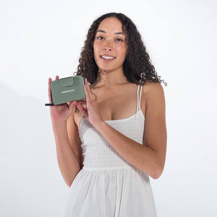 Woman holding a Sherpani Barcelona Aloe Mist Green Anti-theft RFID Mini Wallet on white backdrop. #color_aloe-mist-green