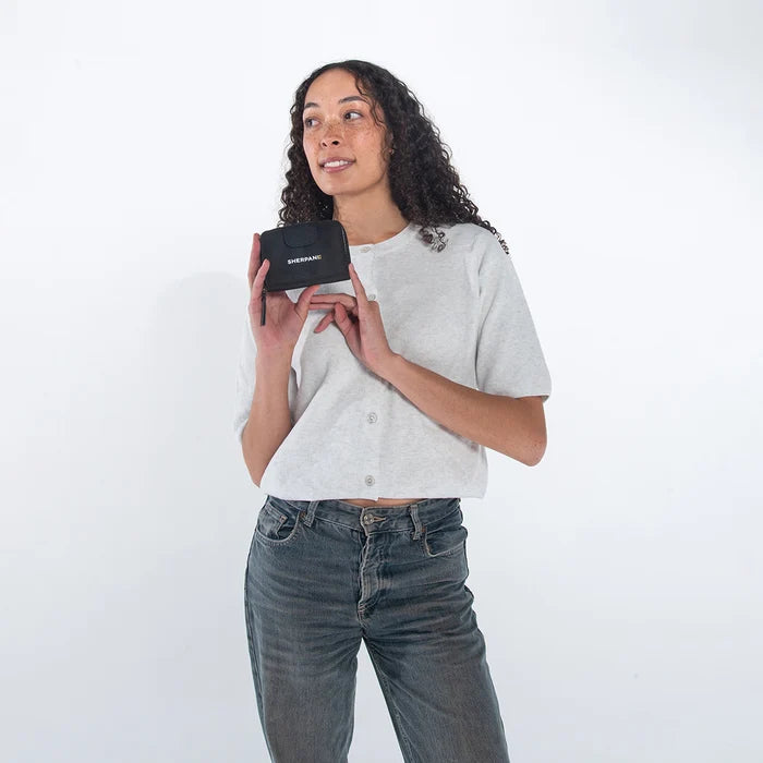 Woman holding a Sherpani Barcelona Carbon Black Anti-Theft Mini Wallet on white backdrop.  #color_carbon-black