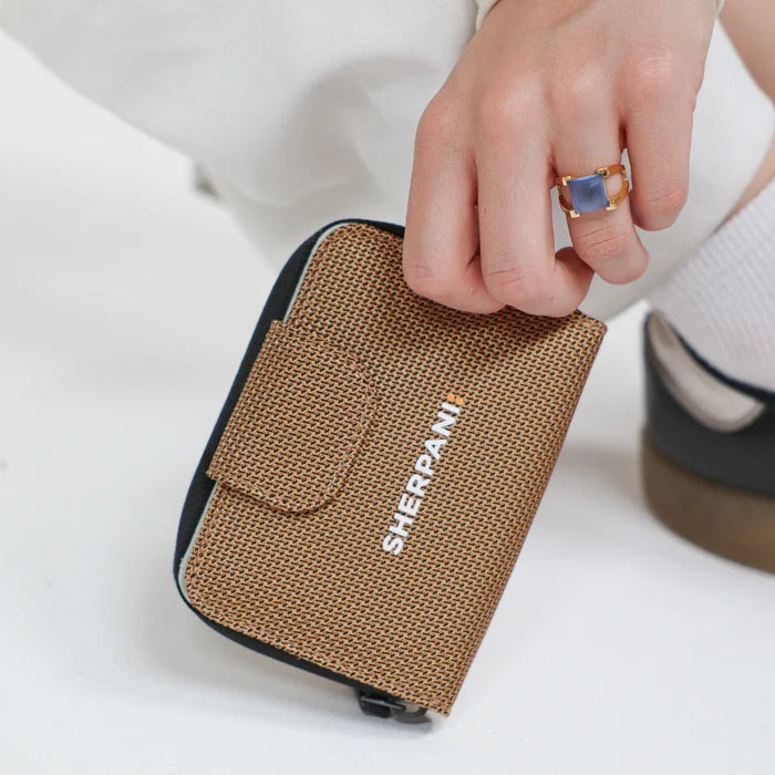 Woman holding a Sherpani Barcelona Sand Anti-Theft Mini Wallet on white backdrop.  #color_sand-tan