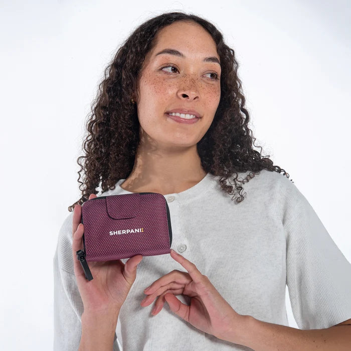 Woman holding a Sherpani Barcelona Smoky Orchid Anti-Theft Mini Wallet on white backdrop.  #color_smoky-orchid-pink