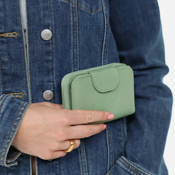 Woman holding a Sherpani Barcelona Olivine RFID Mini Wallet on white backdrop. #color_olivine-green