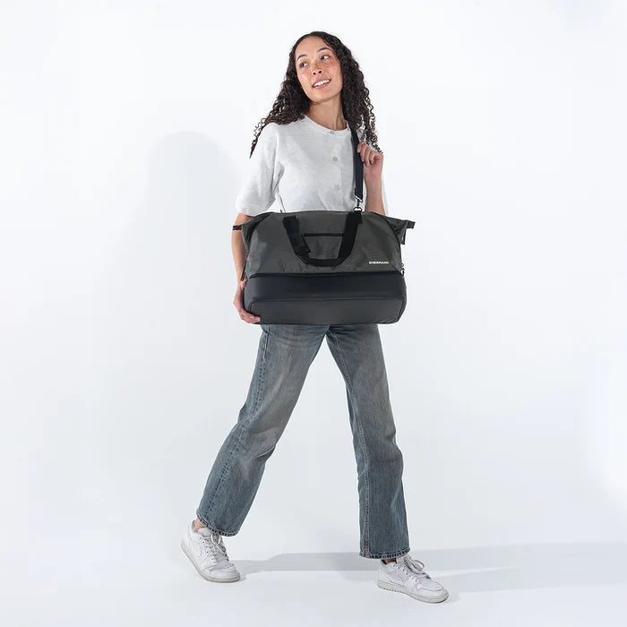 A woman wearing a Sherpani Boston Granite Anti-theft Weekender against a white background. #color_granite-grey