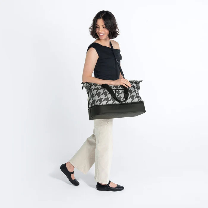A woman wearing a Sherpani Boston Houndstooth Anti-theft Weekender against a white background. #color_houndstooth-print