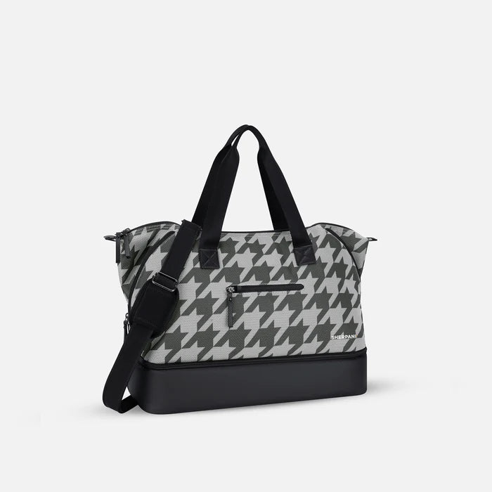 A Sherpani Boston Houndstooth Anti-theft Weekender, 3/4 view showing strap and lockable pocket on white background.  #color_houndstooth-print