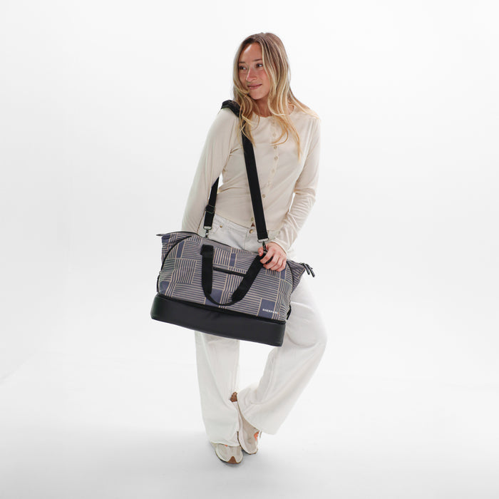 A woman wearing a Sherpani Boston Passport Anti-theft Weekender against a white background. #color_passport-print
