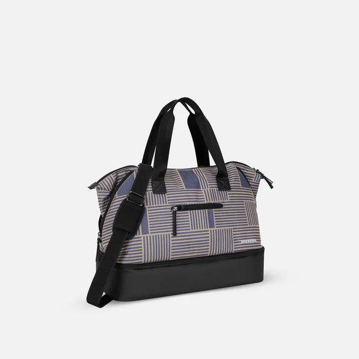 A Sherpani Boston Passport Anti-theft Weekender, 3/4 view showing strap and lockable pocket on white background.  #color_passport-print