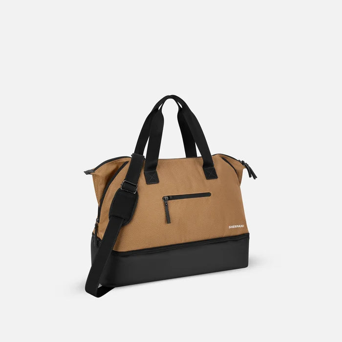 A Sherpani Boston Sand Anti-theft Weekender, 3/4 view showing strap and lockable pocket on white background.  #color_sand-tan