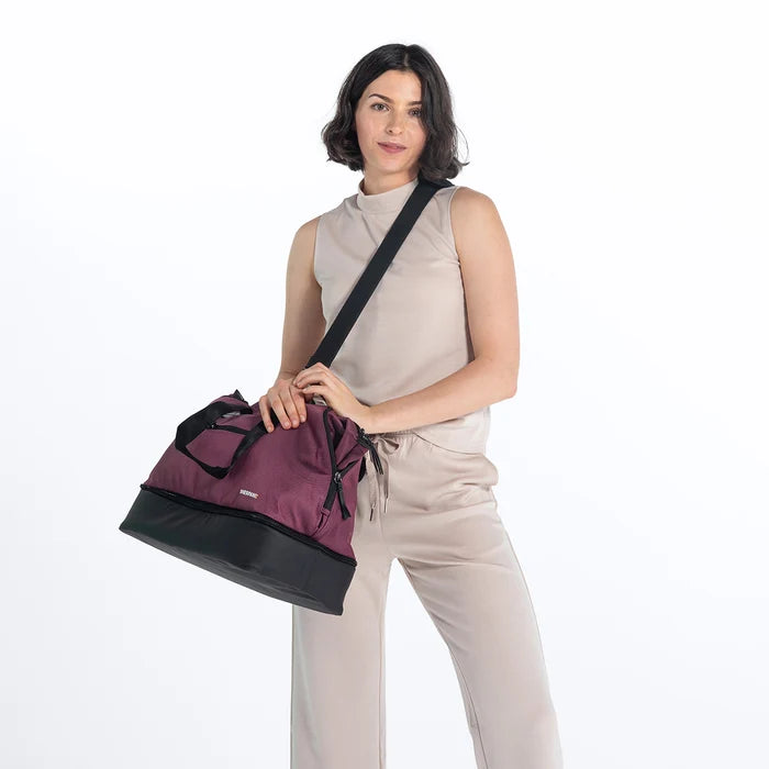 A woman wearing a Sherpani Boston Smoky Orchid Anti-theft Weekender against a white background. #color_smoky-orchid-pink