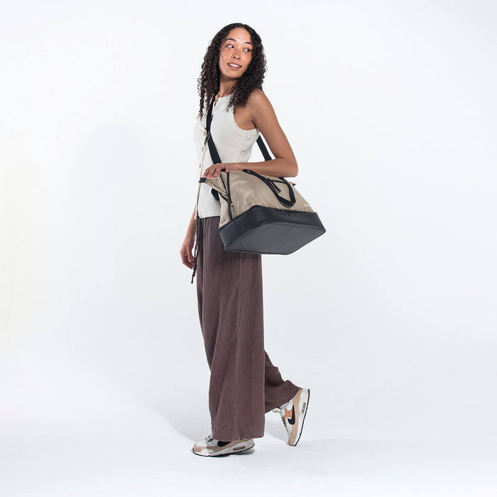 A woman wearing a Sherpani Boston Straw Beige Anti-theft Weekender by crossbody strap against a white background. #color_straw-beige