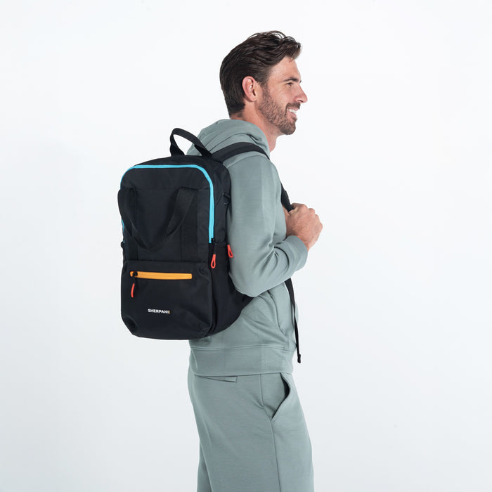 Man wearing a Sherpani Camden Chromatic Black Backpack on his back against white background. #color_chromatic-black