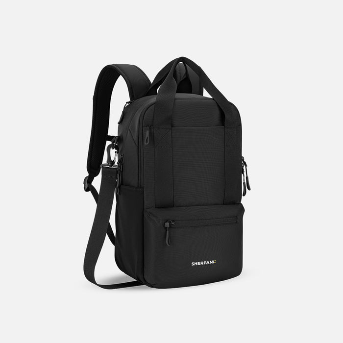 A Sherpani Camden Raven Black Backpack, 3/4 view showing various pockets and strap options on white backdrop.  #color_raven-black