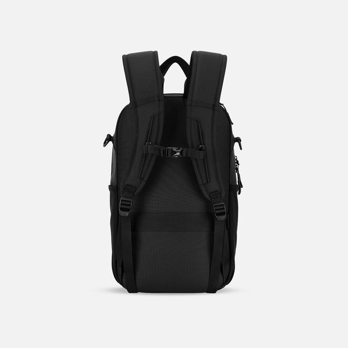 A Sherpani Camden Raven Black Backpack, back view showing the shoulder strap and a luggage strap on a white background. #color_raven-black