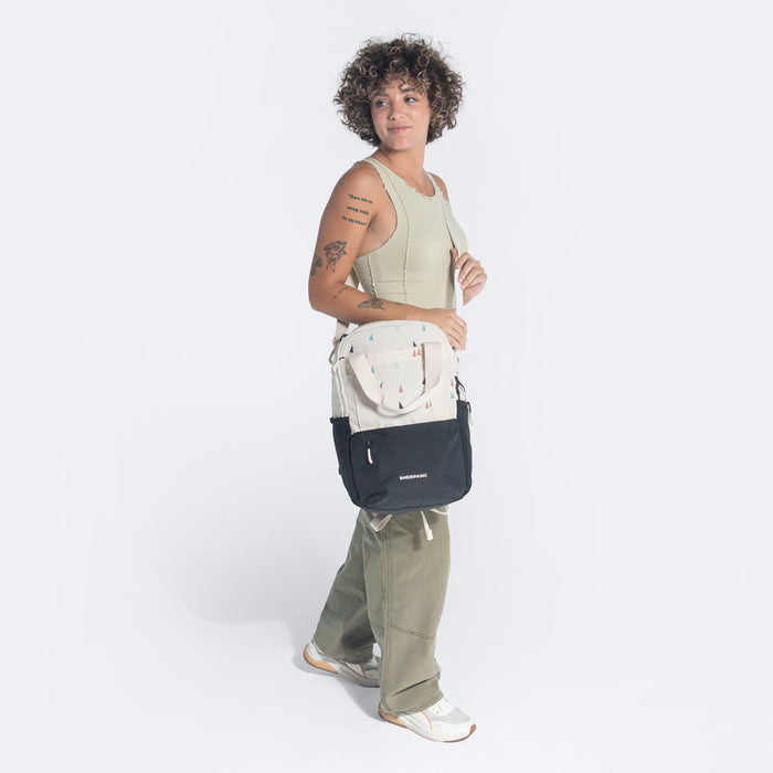 Woman wearing a Sherpani Camden Terrazzo Print Backpack across her shoulder against white background.   #color_terrazzo-print
