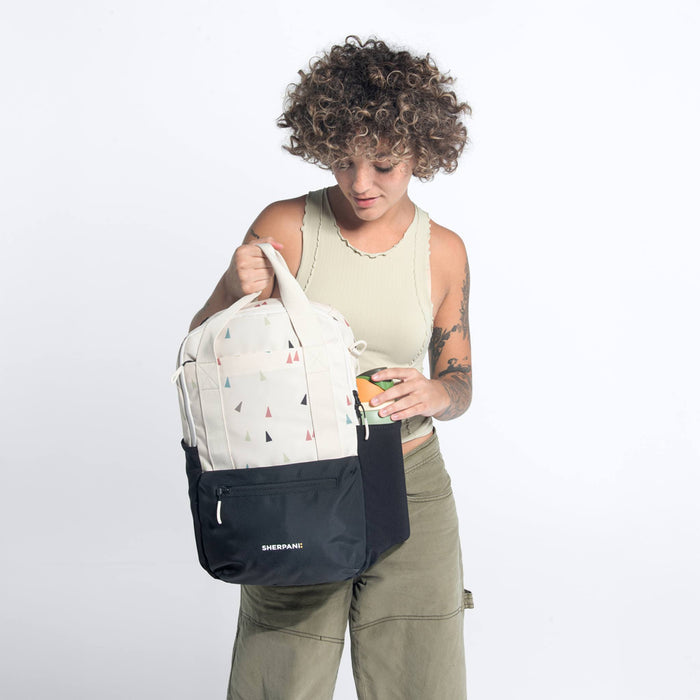 Woman holding a Sherpani Camden Terrazzo Print Backpack by top straps against white background.  #color_terrazzo-print