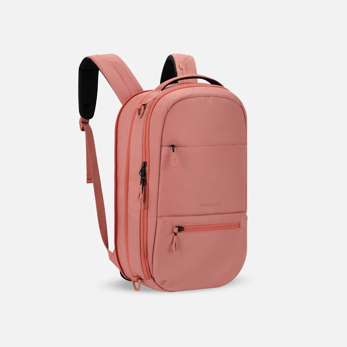 A Sherpani Camden Desert Pink Ultimate Backpack, 3/4 view showing unzipped extender and strap options on white backdrop. #color_desert-pink