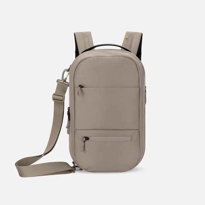A Sherpani Camden Dune Ultimate Backpack, front view showing various pockets and strap options on white backdrop.  #color_dune-tan