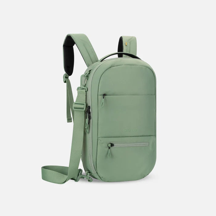 A Sherpani Camden Olivine Ultimate Backpack, 3/4 view showing various pockets and strap options on white backdrop. #color_olivine-green