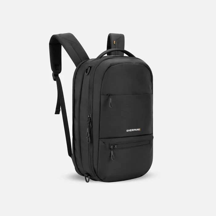 A Sherpani Camden Raven Black Ultimate Backpack, 3/4 view showing unzipped extender and strap options on white backdrop. #color_raven-black