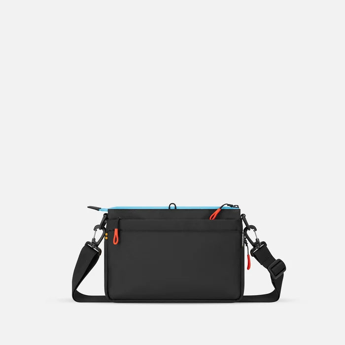 A Sherpani Ceara Chromatic Black Expandable Crossbody, back view showing the back pocket on a white background.   #color_chromatic-black