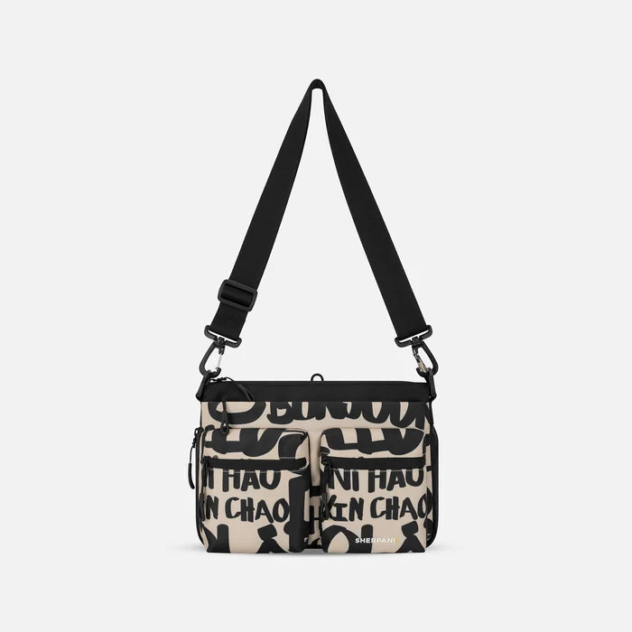 A Sherpani Ceara Ciao Expandable Crossbody, front view showing two front pockets and adjustable strap on a white background.  #color_ciao-print