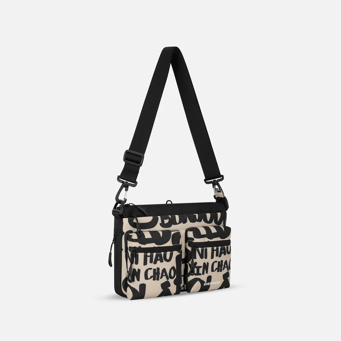 A Sherpani Ceara Ciao Expandable Crossbody, 3/4 view showing two front pockets and the closed expandable pocket on a white background.    #color_ciao-print