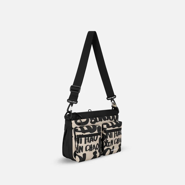 A Sherpani Ceara Ciao Expandable Crossbody, 3/4 view showing two front pockets and the open expandable pocket on a white background.  #color_ciao-print