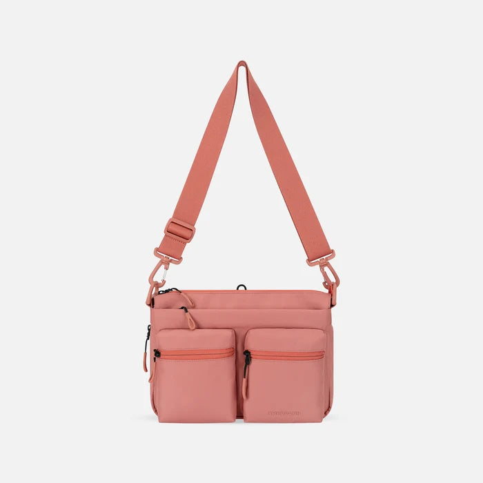 A Sherpani Ceara Desert Pink Expandable Crossbody, front view showing two front pockets and adjustable strap on a white background.  #color_desert-pink
