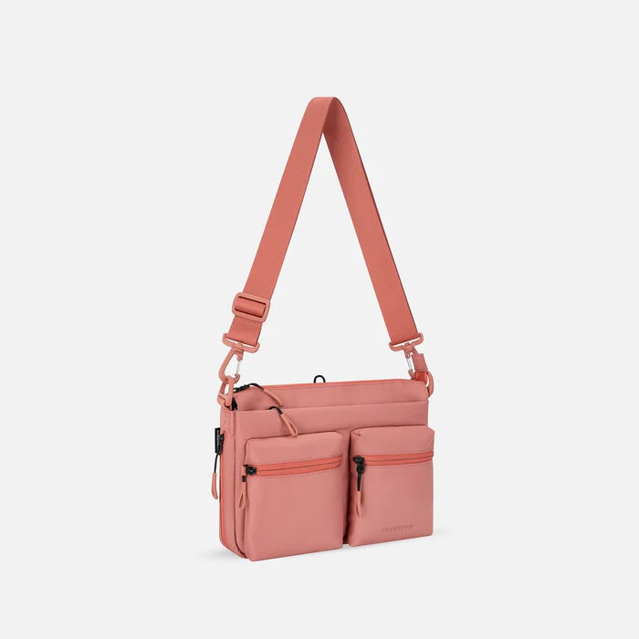 A Sherpani Ceara Desert Pink Expandable Crossbody, 3/4 view showing two front pockets and the closed expandable pocket on a white background.    #color_desert-pink