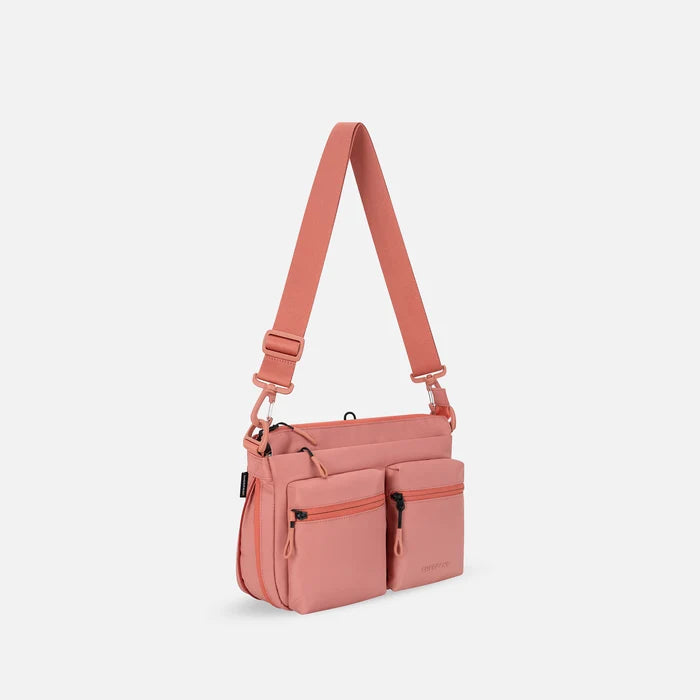 A Sherpani Ceara Desert Pink Expandable Crossbody, 3/4 view showing two front pockets and the open expandable pocket on a white background.  #color_desert-pink