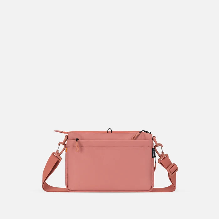 A Sherpani Ceara Desert Pink Expandable Crossbody, back view showing the back pocket on a white background.   #color_desert-pink