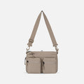 A Sherpani Ceara Dune Expandable Crossbody, front view showing two front pockets and adjustable strap on a white background. #color_dune-tan