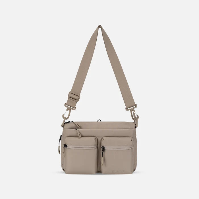A Sherpani Ceara Dune Expandable Crossbody, front view showing two front pockets and adjustable strap on a white background. #color_dune-tan
