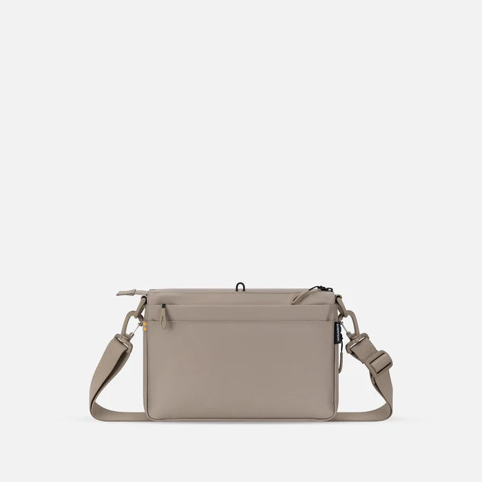 A Sherpani Ceara Dune Expandable Crossbody, back view showing the back pocket on a white background.   #color_dune-tan