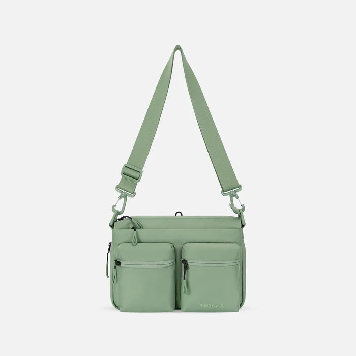 A Sherpani Ceara Olivine Expandable Crossbody, front view showing two front pockets and adjustable strap on a white background.  #color_olivine-green