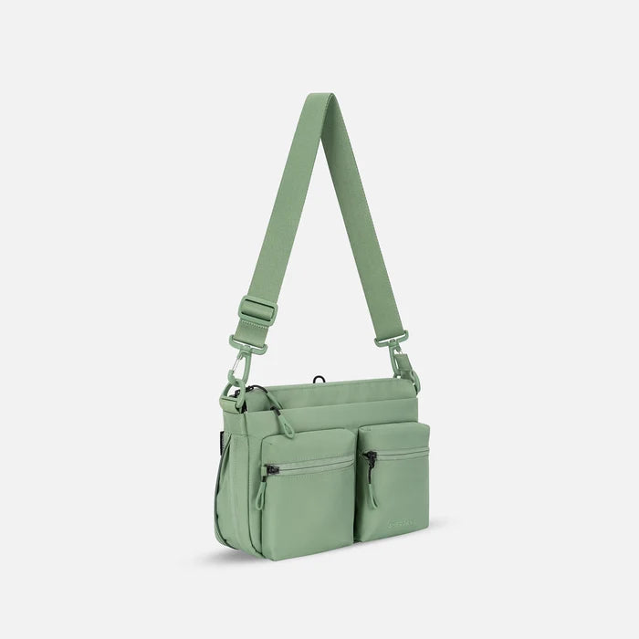 A Sherpani Ceara Olivine Expandable Crossbody, 3/4 view showing two front pockets and the open expandable pocket on a white background.  #color_olivine-green