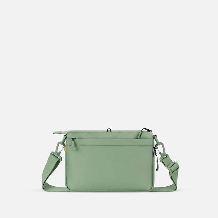A Sherpani Ceara Olivine Expandable Crossbody, back view showing the back pocket on a white background.   #color_olivine-green