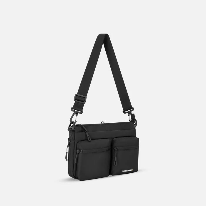 A Sherpani Ceara Raven Black Expandable Crossbody, 3/4 view showing two front pockets and the closed expandable pocket on a white background.   #color_raven-black