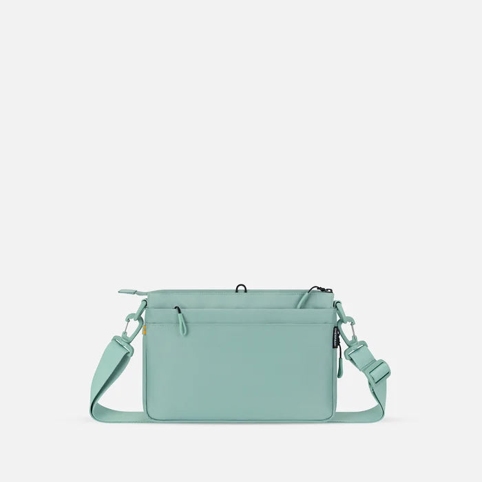 A Sherpani Ceara Surf Blue Expandable Crossbody, back view showing the back pocket on a white background.   #color_surf-blue
