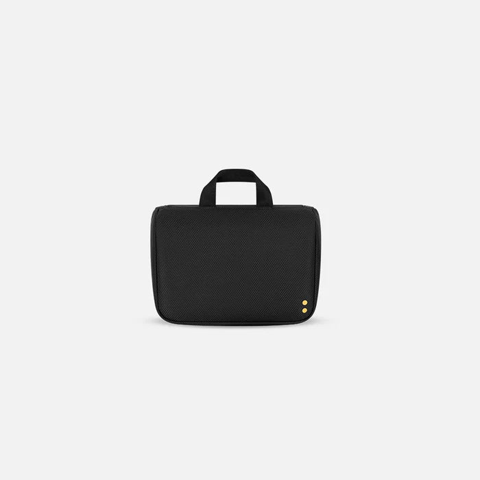 A Sherpani Co-Pilot Carbon Black Travel Toiletry Case, back view showing black backside on white backdrop. #color_carbon-black