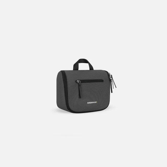 A Sherpani Co-Pilot Granite Travel Toiletry Case, 3/4 view showing handheld strap and zipper pockets on white backdrop. #color_granite-grey