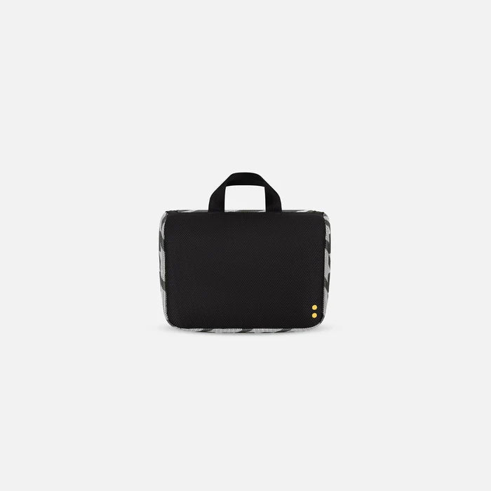 A Sherpani Co-Pilot Houndstooth Travel Toiletry Case, back view showing black backside on white backdrop. #color_houndstooth-print
