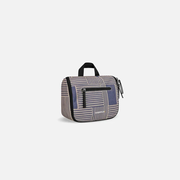 A Sherpani Co-Pilot Passport Travel Toiletry Case, 3/4 view showing handheld strap and zipper pockets on white backdrop. #color_passport-print