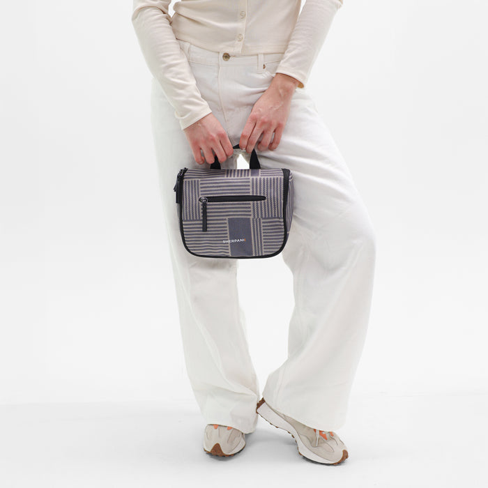 Woman holding a Sherpani Co-Pilot Passport Travel Toiletry Case against white backdrop. #color_passport-print