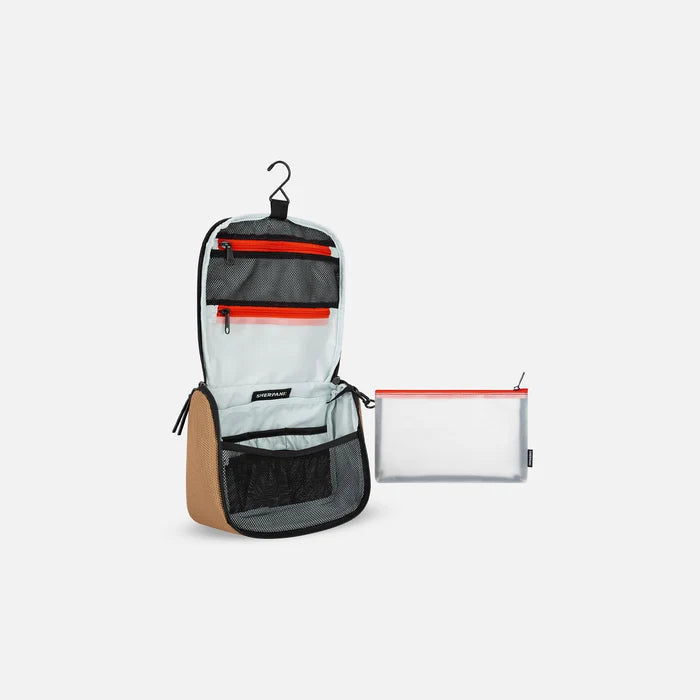 A Sherpani Co-Pilot Sand Travel Toiletry Case, 3/4 view showing interior pockets  against white backdrop. #color_sand-tan