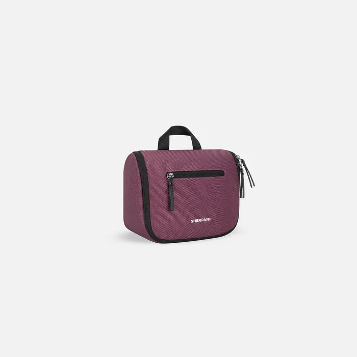 A Sherpani Co-Pilot Smoky Orchid Travel Toiletry Case, 3/4 view showing handheld strap and zipper pockets on white backdrop. #color_smoky-orchid-pink