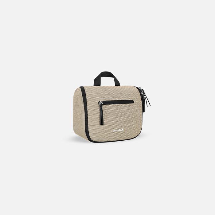 A Sherpani Co-Pilot Straw Beige Travel Toiletry Case, 3/4 view showing pockets and handle against white background.  #color_straw-beige