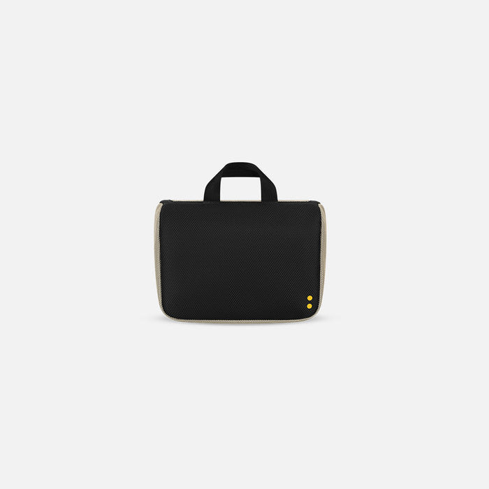 A Sherpani Co-Pilot Straw Beige Travel Toiletry Case, back view showing black backside against white background. #color_straw-beige