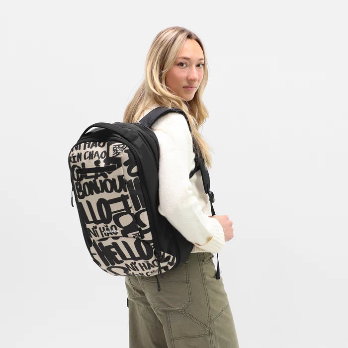 A woman wearing a Sherpani Crew Ciao Travel Backpack on her back against a white background. #color_ciao-print