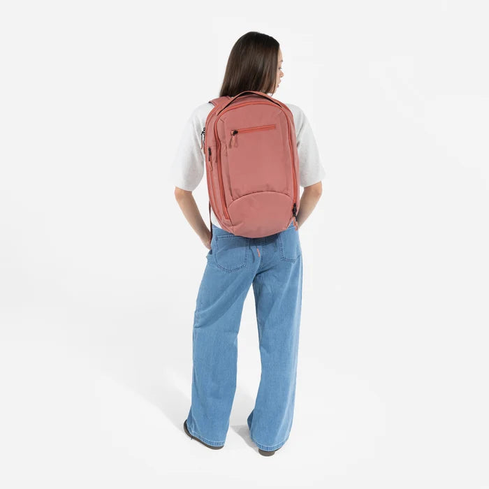 A woman wearing a Sherpani Crew Desert Pink Travel Backpack on her back against a white background. #color_desert-pink