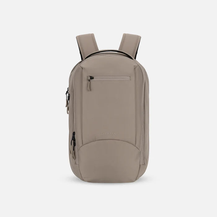 A Sherpani Crew Dune Travel Backpack, front view showing lockable zippers and different straps against a white background. #color_dune-tan
